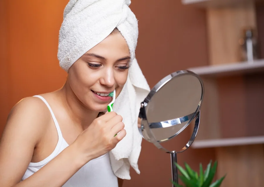 Frau putzt sich ordentlich die Zähne vor Spiegel im Badezimmer