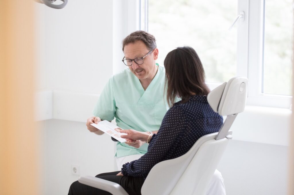 Zahnarzt Dr. Jürgen Burg bespricht mit Patienten aus Allmersbach im Tal, welche Behandlungsschritte nötig sind.